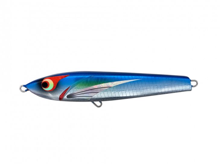 A topwater stickbait lure with a reflective surface and multicolored design, displayed on a table with other fishing lures in the background.
